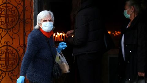 Peregrinos griegos portan mascarillas y guantes para asistir al oficio del Buen Viernes en Atenas