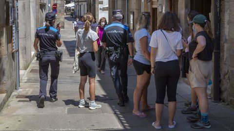 La plantilla de la Policía Local de Santiago, en la imagen dos agentes patrullan por la calle, se ve obligada a realizar horas extra para atender todos los servicios necesarios