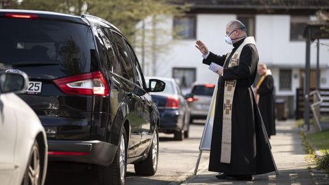 Un sacerdote bendice a vehculos que circulan por una calle de Munich