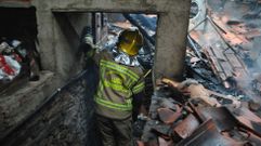 Un bombero examina el interior de la casa que se incendi este jueves en la parroquia de Doade (Sober)