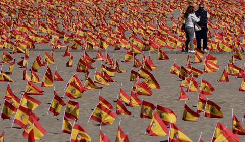 Dos personas pasean por la Playa de la Patacona de Alboraya en la que se han colocado un total de 53.000 banderas de Espaa en homenaje a los espaoles fallecidos por coronavirus, en Alboraya, Valencia (Espaa) a 4 de octubre de 2020. La iniciativa, impulsada por la Asociacin Nacional de Vctimas y Afectados por Coronavirus (ANVAC), colocaron esta madrugada las banderas en la playa de la Patacona de Alboraia (Valencia)