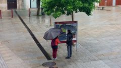 Una pareja de turistas consultando un panel informativo en la plaza de Espaa de Monforte