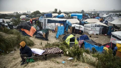 Un inmigrante fala polo mbil durante a evacuacin do campamento coecido como a Xungla de Calais