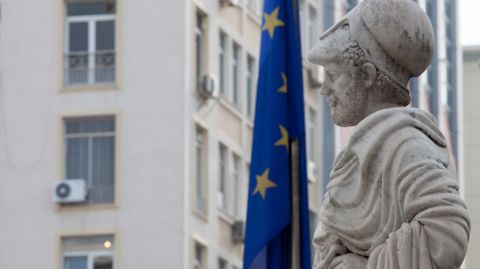 Una estatua de Pericles mira de frente a una bandera de la Unión Europea en la Calle Stadiou.
