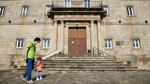 Un hombre con mascarilla pasea con su hija frente a la puerta del parador de turismo de Monforte, cerrado por la crisis del coronavirus