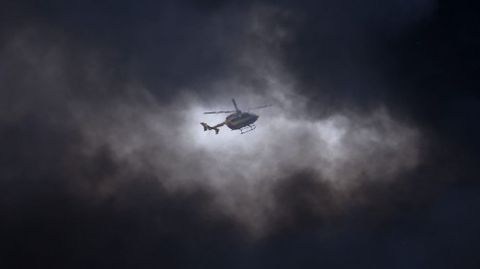 Un helicptero sobrevuela entre la gran columna de humo que se eleva sobre un almacn de una zona industrial en La Courneuve, en Francia. 