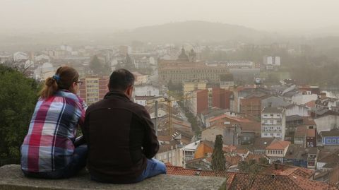Una pareja observa el sur del casco urbano de Monforte sentada en un banco junto al parador de turismo, en el monte de San Vicente