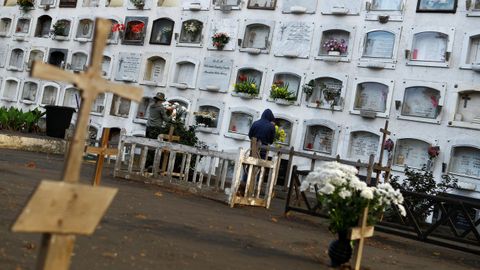 Dos personas limpian la ceniza del volcn Cumbre Vieja en la tumba de un familiar en el cementerio de Los Llanos de Aridane