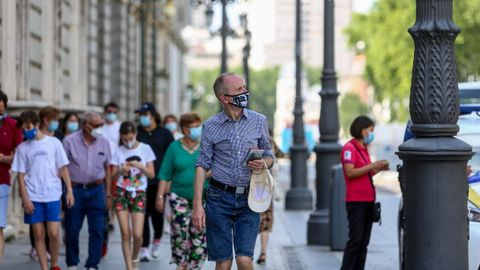 Viandantes con mascarillas en las inmediaciones del Palacio Real, en Madrid