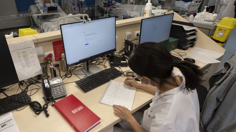 Una sanitaria del Hospital Clínic de Barcelona trabaja tomando notas a mano tras el ciberataque