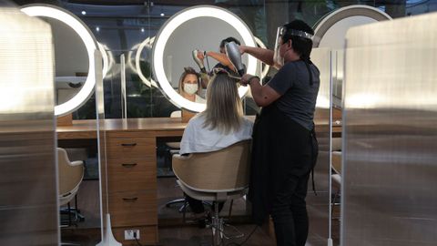 Una peluquera atiende a una cliente en medio de mamparas en Sao Paulo, Brasil