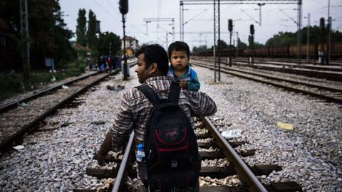 Un inmigrante caminando con su hijo por unas vas de tren en Gevgelija, cerca de la fronte entre Macedonia y Grecia