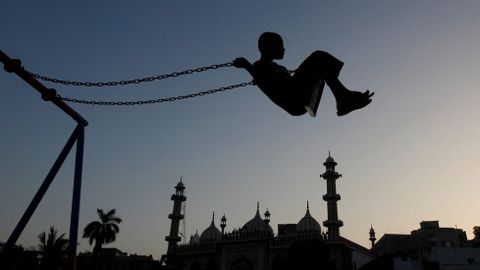 Un chico se balancea en un columpio cerca de la mezquita de Karachi, en Paquistn