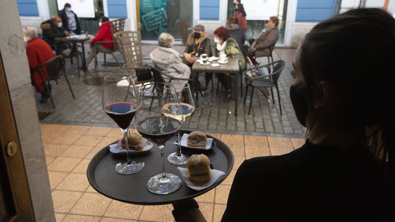 Una camarera se dispone a servir en una terraza de un restaurante de Avilés