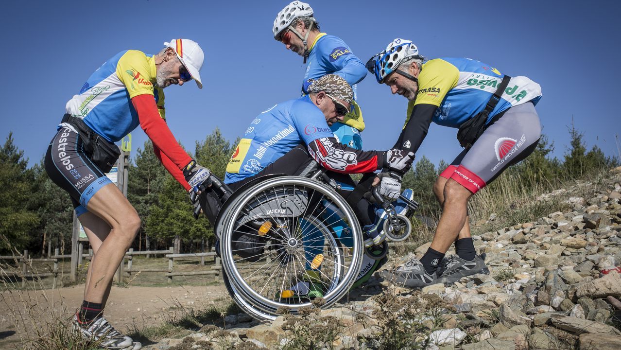 Desde la ventana Historia de un Maceto-huerto urbano.�lvaro y Jorge Pino ayudan a Suso Valverde a subir a la Cruz de Ferro en su handbike