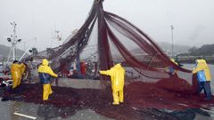 Foto de archivo de marineros de un cerquero gallego trabajando con las redes en el puerto de Celeiro