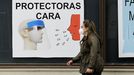 Una mujer pasa delante de un anuncio de pantallas protectoras contra el coronavirus en una calle de Monforte