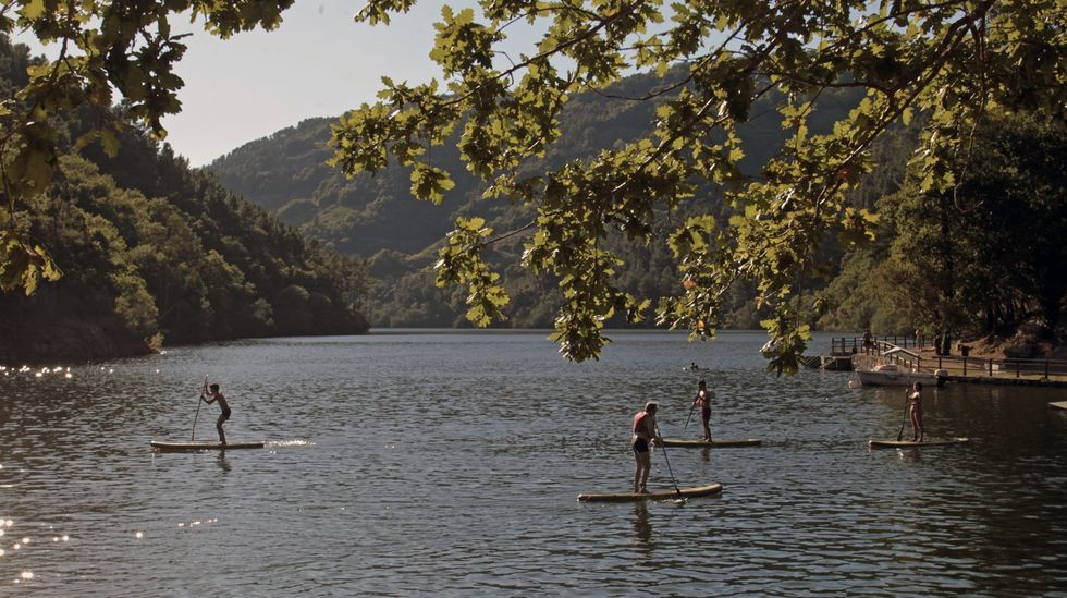 As son las visitas guiadas por la Compostela Oculta.Turistas reman en unas tablas de surf frente a la playa fluvial de A Cova, en el rio Mio entre Chantada y O Saviao