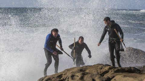 Barnacle workers moving away from a wave in O Roncudo, in Corme, in a file image