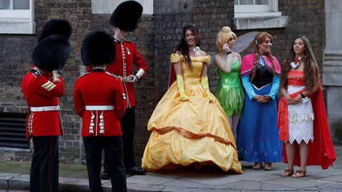 Varios miembros de la guardia real de Reino Unido junto a cuatro mujeres disfrazadas de las princesas Disney. 