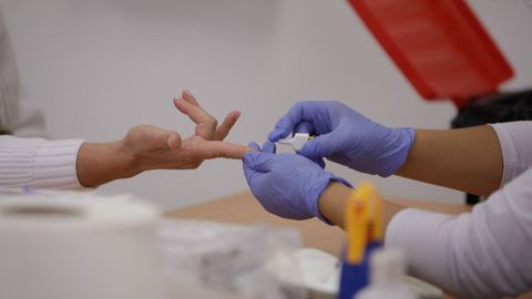 Personal sanitario de Cruz Roja saca sangre de un dedo a una persona para realizar el test rpido de deteccin de anticuerpos IgG e IgM en Madrid