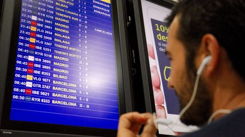 Un viajero frente al panel de información de vuelos de Lavacolla