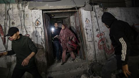 Varios civiles palestinos buscan supervivientes y cadáveres entre los escombros.
