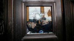 Agentes del Capitolio observan los destrozos en una ventan