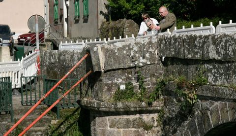 Varios vecinos observan la zona daada del puente medieval. 