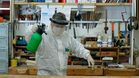 Un carpintero italiano desinfecta su carpintera para prepararla para la vuelta al trabajo