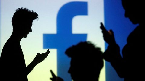 Usuarios de las redes sociales delante de un logo de Facebook