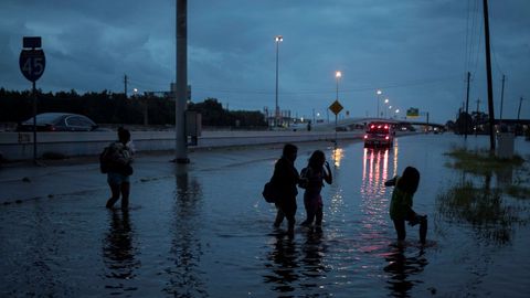 Un grupo de personas pasean a travs de la inundacin dejada por el huracn Harvey