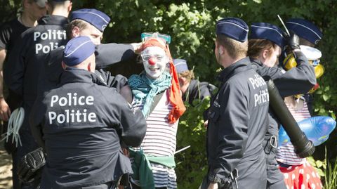 Un manifestante vestido de payaso es detenido durante una protestas ante la sede de la OTAN en Bruselas (Blgica).