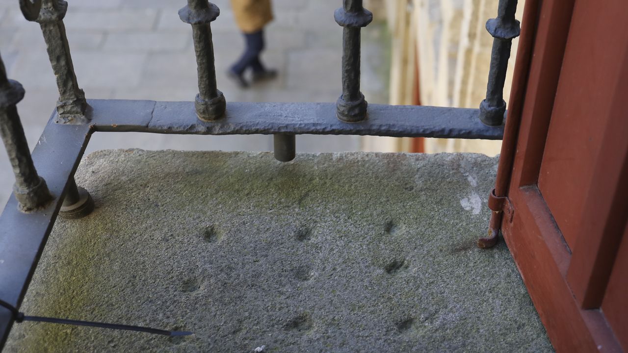 Los tableros del tres en rayaesparcidospor Compostela.Jorge Vila con un ejemplar de su libro ante la torre del homenaje y el antiguo convento de San Vicente do Pino, actual parador