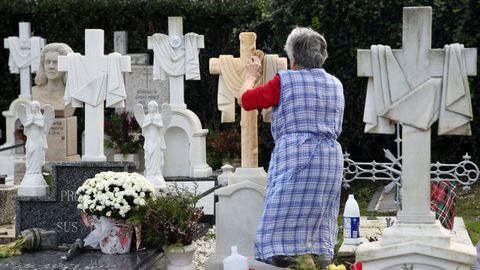 Unha muller limpa as lousas de cara o da de defuntos no cemiterio de Santa Maria