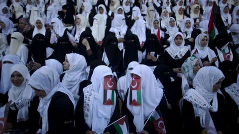 Novias palestinas, cubriendo sus rostros con banderas palestinas y turcas, participan en una boda mltiple en Gaza. 