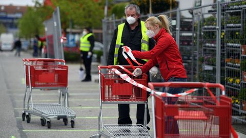 Empleados de una tienda de Alemania preparan la zona de los clientes minutos antes de la apertura