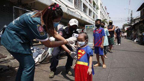 Voluntarios tailandeses controlan la temperatura corporal de una nia durante una distribucin gratuita de alimentos 