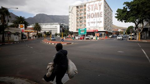 Un hombre camina por una calle sudafricana vaca  