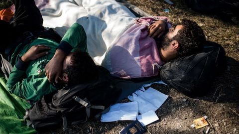 Un grupo de inmigrantes y refugiados descansan al lado de una via de ferrocarril en Serbia