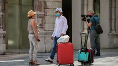 Un cmara de televisin trabaja junto a dos turistas con mascarilla en una calle de Oviedo