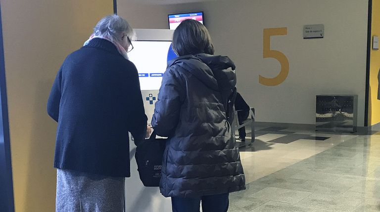 Dos pacientes sacan su cita en una de las máquinas de las consultas externas del HUCA