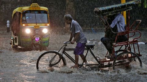 Un hombre pedalea a travs de las lluvias del monzn en Nueva Delhi (India)