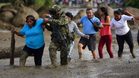 Un soldado ayuda a una mujer despues de una avalancha del ro La Paila en Colombia