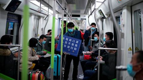 Un miembro de la empresa muestra un cartel que dice:  Llevar siempre mascarilla, evitar aglomeraciones y mostrar el cdigo para escanear al salir del tren .