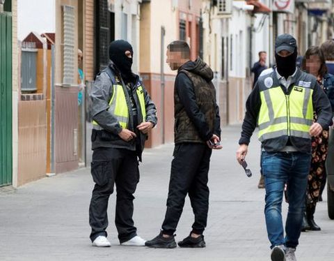 Dos agentes de la policía caminan y hablan con algunas personas durante el registro de la casa en Sevilla del presunto yihadista 