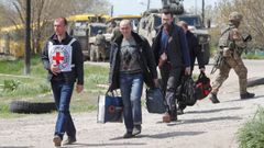 Civiles evacuados de la planta de Azovstal caminan tras un miembro de Cruz Roja en la localidad de Bezimenne, en la provincia de Donetsk