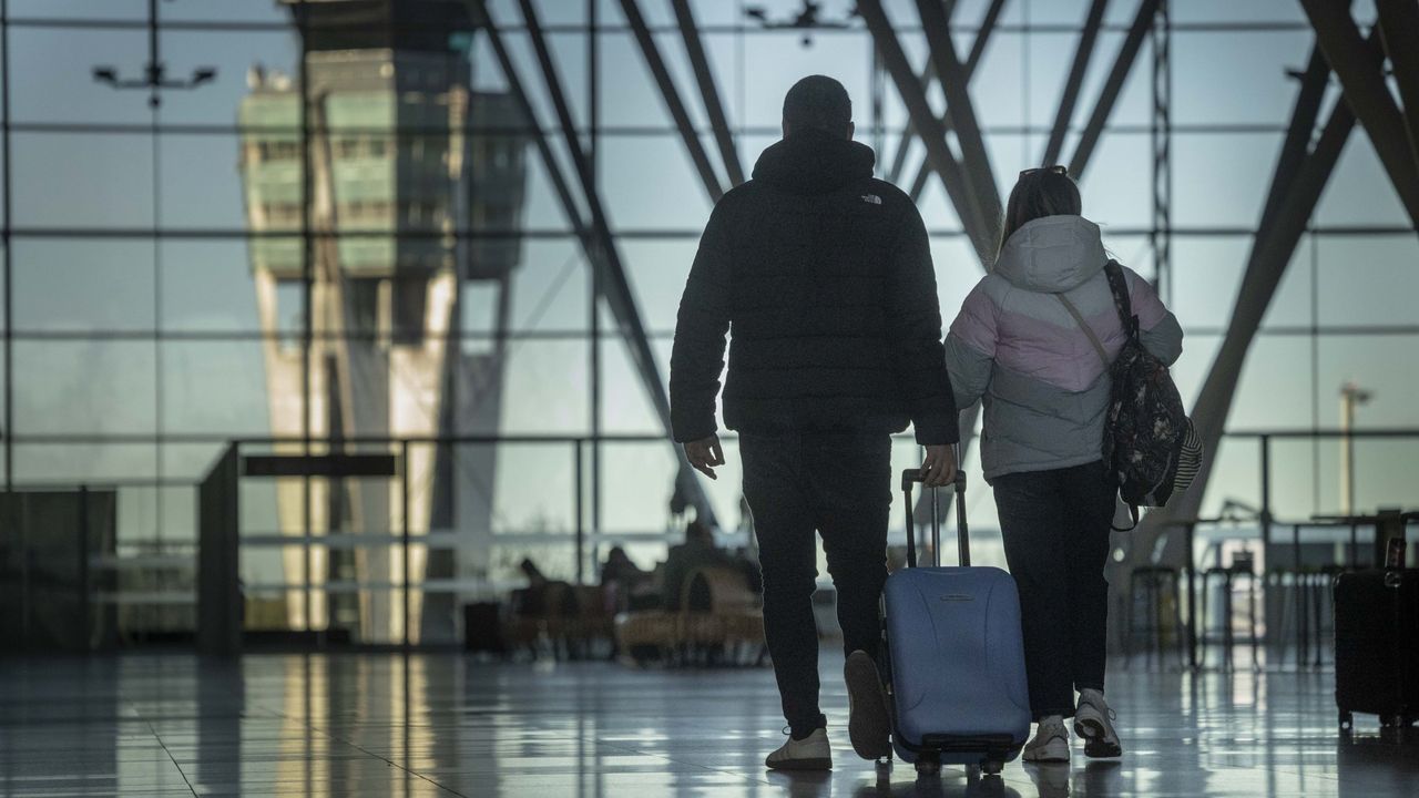 Dos pasajeros caminan con sus maletas por la terminal del aeropuerto de Santiago-Rosal�a de Castro.