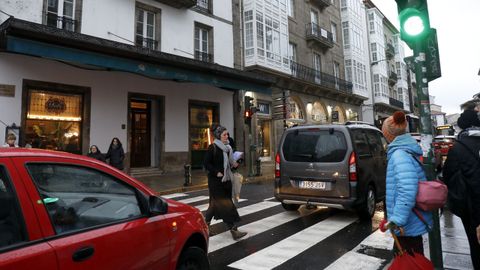 Un viandante cruza con el semáforo en verde para los vehículos en el paso de cebra que une plaza de Galicia con Fonte de Santo Antonio