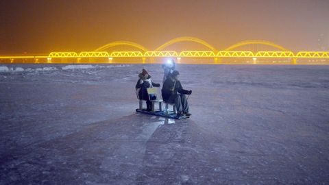 Un grupo de visitantes atraviesa en trineo el congelado ro Songhua, junto al festival de hielo de Harbin.